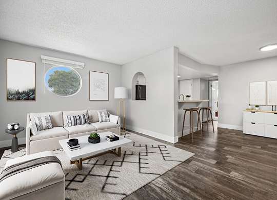 Model Living Room with Wood-Style Flooring and View of Kitchen at Stillwater Apartments located in Glendale, AZ.