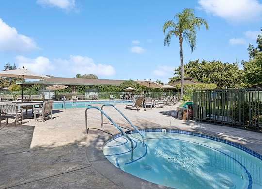 Swimming pool with chairs and tables and umbrellas at Walnut Creek Manor Apartments in Walnut Creek, CA