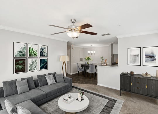 Model Living Room with Carpet and View of Dining Room with Wood-Style Flooring at Shadow Ridge Apartments in Riverdale, GA.