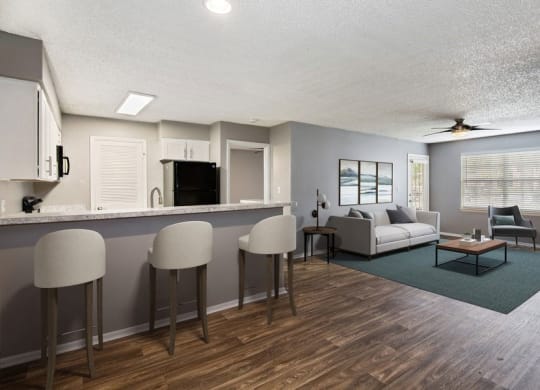 Model living room and kitchen with bar seating and wood floors