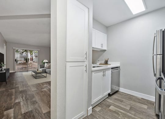 Model Kitchen with White Cabinets, Wood-Style Flooring and View of Living Room at Crystal Creek Apartments located in Phoenix, AZ.