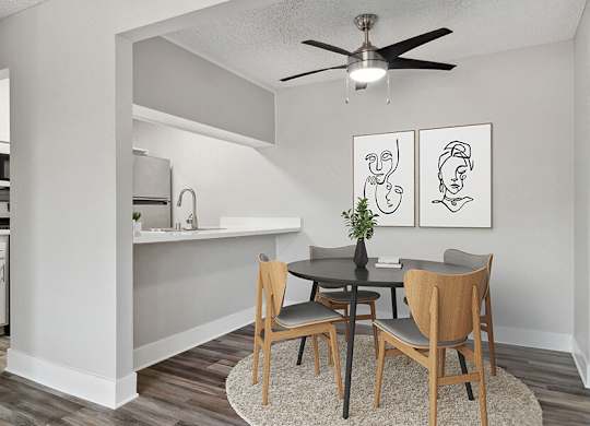 Model Dining Room with Wood-Style Flooring and View of Kitchen at Fullerton Hills Apartments located in Fullerton, CA.