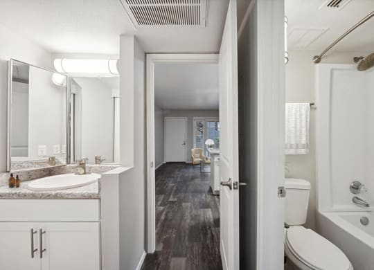Model Bathroom with White Cabinets, Wood-Style Flooring and Shower/Tub at Country Club Verandas Apartments located in Mesa, AZ.