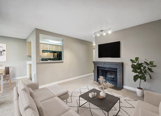 Model Living Room with Carpet, Fireplace and View of Kitchen at Grammercy Apartments located in Renton, WA.