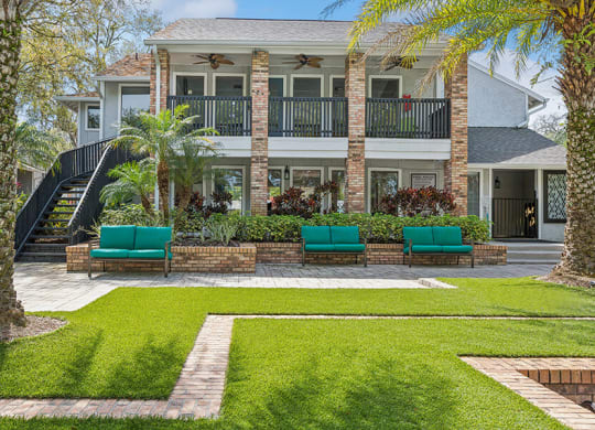 Exterior Community Clubhouse and Landscape with Lounge Furniture at Grand Pavilion Apartments in Tampa, FL.