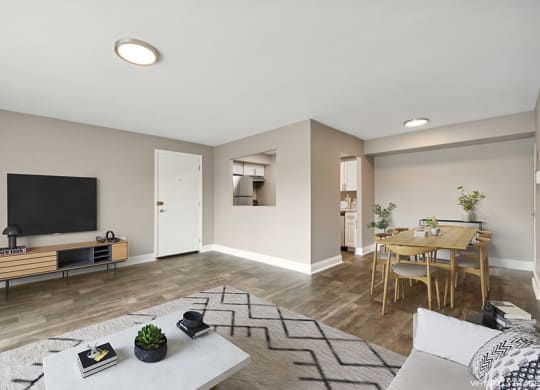 Model Living Room with Wood-Style Flooring and View of Kitchen/Dining Area at Heights at Marlborough Apartments located in Marlborough, MA.