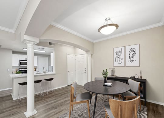 Model Dining Room with Wood-Style Flooring and View of Kitchen at Allure North Dallas Apartments located in Dallas, TX.