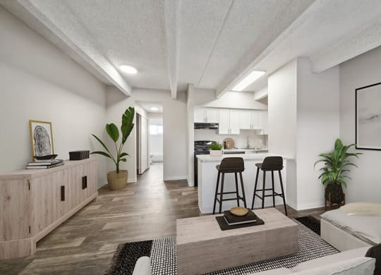 Model Living Room with Wood-Style Flooring and View of Kitchen at Esprit at Cherry Creek Apartments in Glendale, CO.