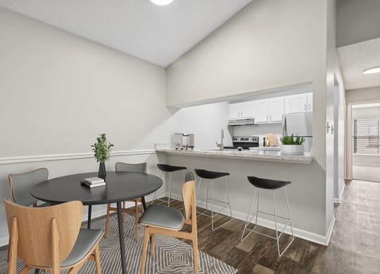 Model Dining Room and Kitchen with Wood-Style Flooring and Hallway View at Rosehill Preserve Apartments located in Orlando, FL.