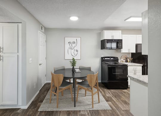 Model Dining Room with Wood-Style Flooring and View of Kitchen with White Cabinets at Solano Springs Apartments located in Tucson, AZ.