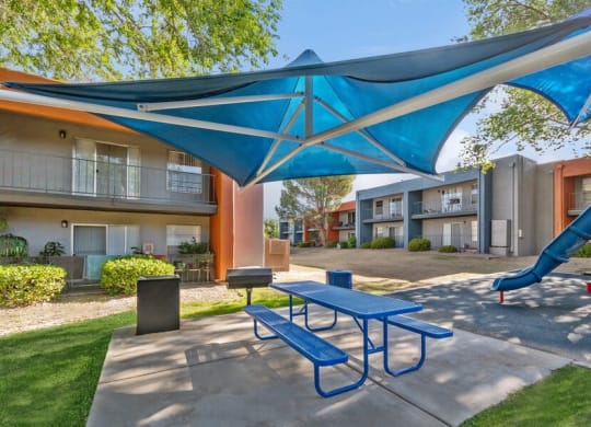 Outdoor BBQ Area with Blue Canopy and Picnic Table at Indigo Park Apartments in Albuquerque, NM.