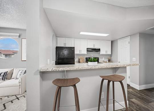 Model Kitchen with White Cabinets and Wood-Style Flooring at Stillwater Apartments located in Glendale, AZ.