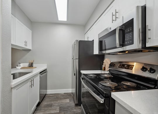Model Kitchen with White Cabinets and Wood-Style Flooring at Crystal Creek Apartments located in Phoenix, AZ.