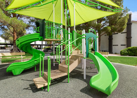 Community Playground with two Slides and a Green Canopy at Meadow Ridge Apartments in Las Vegas, NV.