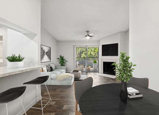 Model Dining Room with Wood-Style Flooring and View of Living Room with Fireplace at Rosehill Preserve Apartments located in Orlando, FL.