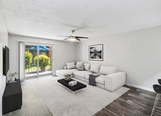 Model Living Room with Wood-Style Flooring and Patio Accessibility at Indigo Park Apartments located in Albuquerque, NM.