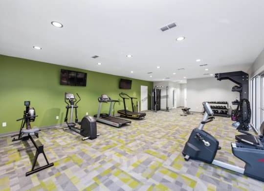 a gym with weights and cardio equipment in a building with green walls