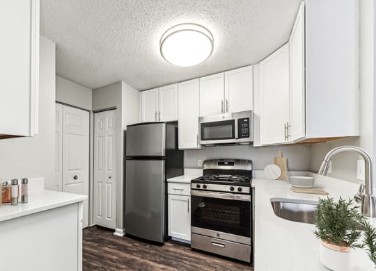 Model Kitchen with White Cabinets and Wood-Style Flooring at Commons at Haynes Farm Apartments in Shrewsbury, MA.