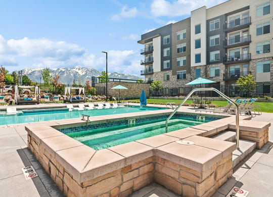 Community Hot Tub and Swimming Pool with Pool Furniture at Seven Skies Apartments located in Sandy, UT.