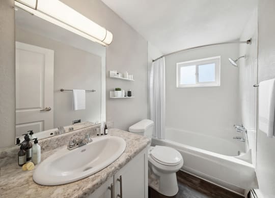 Model Bathroom with White Cabinets, Wood-Style Flooring and Shower/Tub at Esprit at Cherry Creek Apartments in Glendale, CO.