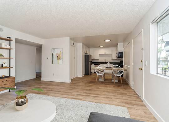 Model Living Room and Kitchen with Wood-Style Flooring at Palmilla Apartments located in San Diego, CA.