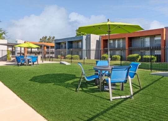 Outdoor Corn Hole Area with Covered Patio Furniture at Indigo Park Apartments in Albuquerque, NM.