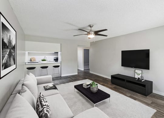 Model Living Room with Wood-Style Flooring and View of Kitchen at Indigo Park Apartments located in Albuquerque, NM.