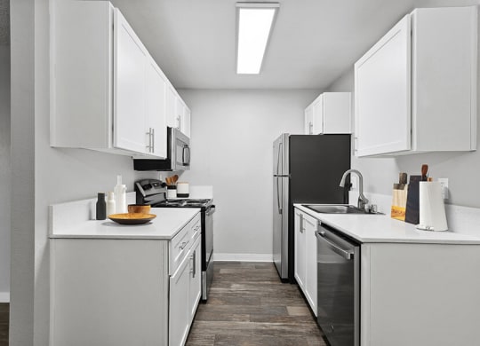 Model Kitchen with White Cabinets and Wood-Style Flooring at The Archer Apartments in Sacramento, CA.