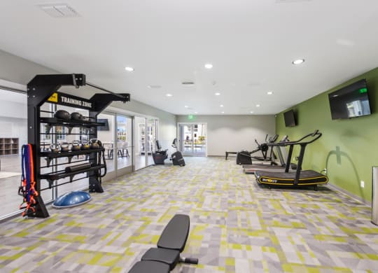 a workout room with weights and cardio equipment and a wall mounted tv
