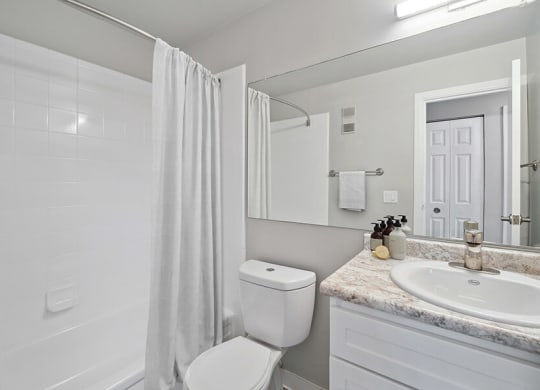 Model Bathroom with Bathtub/Shower, Wood-Style Flooring & White Cabinets at Waterfront Apartments in Lakewood, CO.