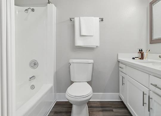 Model Bathroom with White Cabinets, Wood-Style Flooring and Shower/Tub at Fullerton Hills Apartments located in Fullerton, CA.