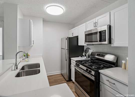 Model modern kitchen with black appliances and white cabinets.