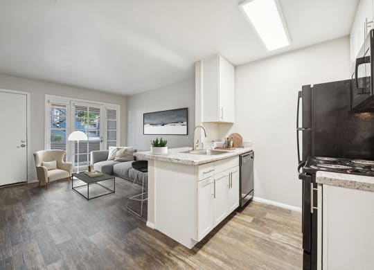 Model Kitchen with White Cabinets, Wood-Style Flooring and View of Living Room at Country Club Verandas Apartments located in Mesa, AZ.