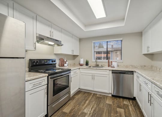 Model Kitchen with White Cabinets and Wood-Style Flooring at Grammercy Apartments located in Renton, WA.