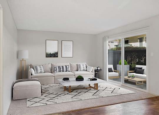 Model Living Room with Carpet and Patio Accessibility at Los Gatos Landing Apartments located in San Jose, CA.