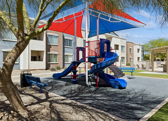 Community Playground with Slide and Blue/Red Canopy at Ridgeline Apartments in Tucson, AZ.