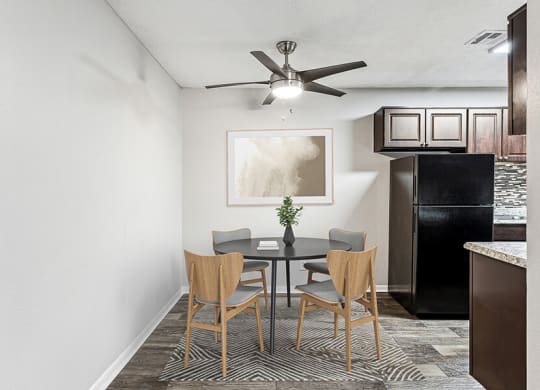 Model Dining Room with Wood-Style Flooring and View of Kitchen at Paramont Apartments in Duluth, GA.