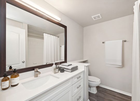 Model Bathroom with Wood-Style Flooring, White Cabinets & Shower/Tub at Allure North Dallas Apartments located in Dallas, TX.