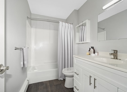 Model Bathroom with White Cabinets and Wood-Style Flooring at Stone Ends Apartments in Stoughton, MA.