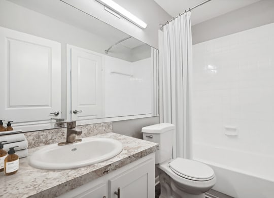 Model Bathroom with Wood-Style Flooring, White Cabinets & Shower/Tub at Rosehill Preserve Apartments located in Orlando, FL.