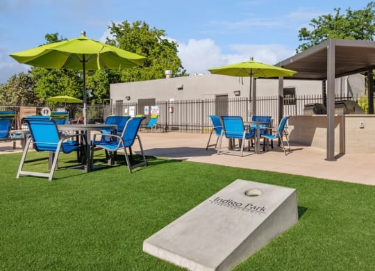Outdoor Corn Hole and BBQ Area with Covered Patio Furniture at Indigo Park Apartments in Albuquerque, NM.