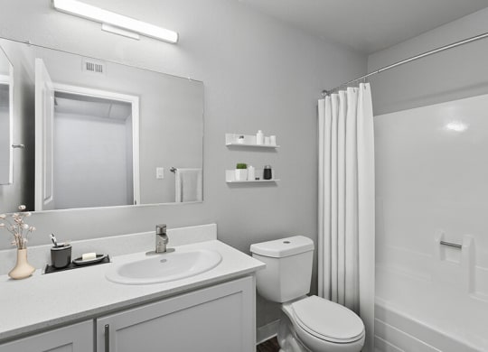 Model Bathroom with White Cabinets and Wood-Style Flooring at The Archer Apartments in Sacramento, CA.
