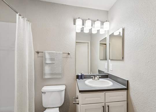 Model Bathroom with White Cabinets, Wood-Style Flooring & Shower/Tub at Lake Cameron Apartments located in Apex, NC.