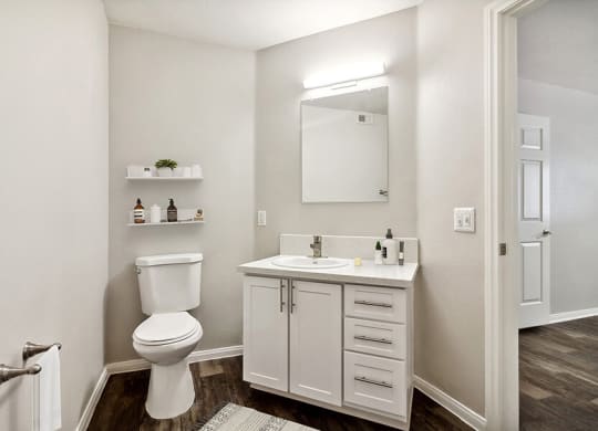 Model Bathroom with Wood-Style Flooring and White Cabinets at Loma Vista Apartments in Las Vegas, NV.