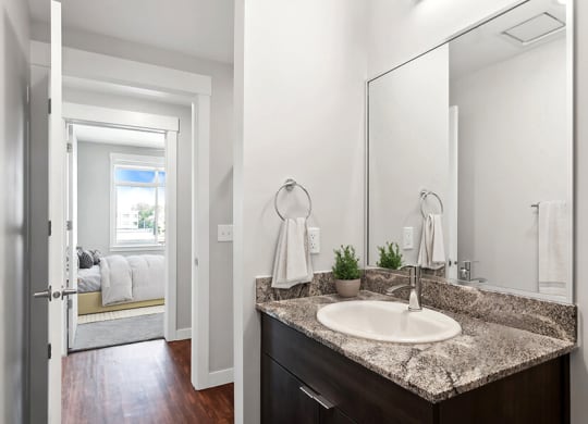Model Bathroom with Wood-Style Flooring and Dark Oak Cabinets at Seven Skies Apartments located in Sandy, UT.