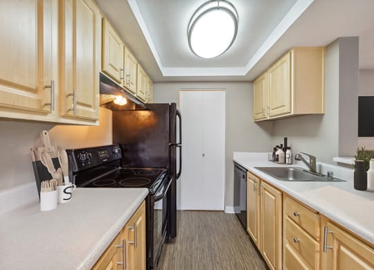 Model Kitchen with Dark Wood Cabinets and Wood-Style Flooring at Grammercy Apartments located in Renton, WA.
