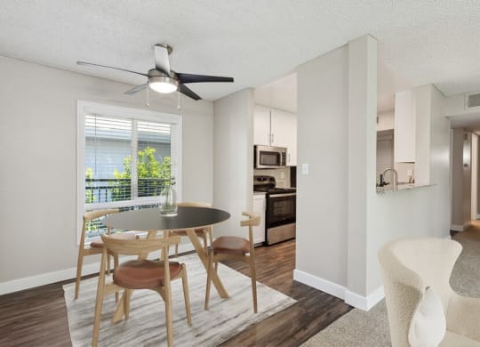 Model dining area with a table and chairs and a kitchen in the background