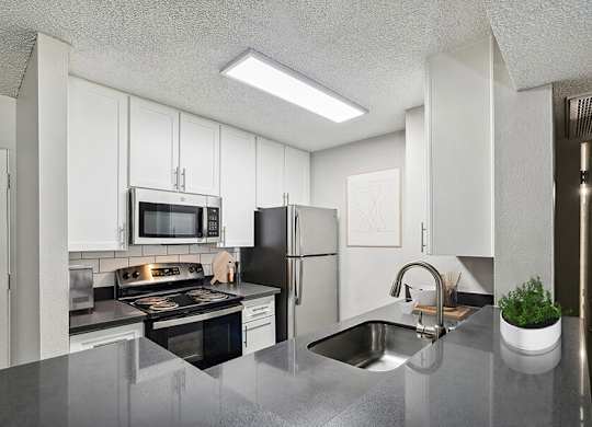 Model Kitchen with White Cabinets and Wood-Style Flooring at Madison Park Apartments located in Anaheim, CA.