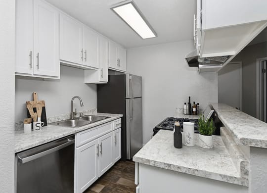 Model Kitchen with White Cabinets and Wood-Style Flooring at The Meritage Apartments in Vallejo, CA.