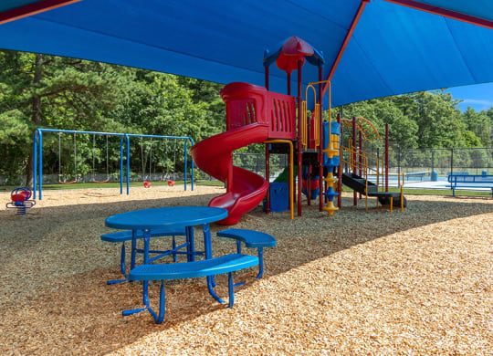 Community Playground with a Slide, Blue Canopy and Swing Set at Village at Marshfield Apartments located in Marshfield, MA.